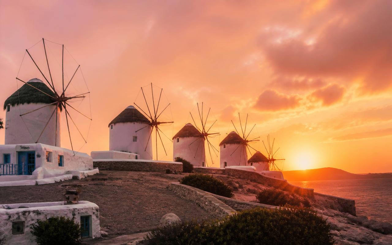The famous white windmills of Mykonos at golden hour overlooking the Aegean Sea